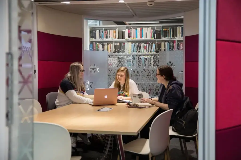 Three students studying in a pod in the library at Cardiff campus