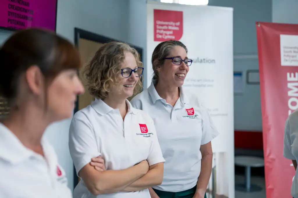 Three students stood together, smiling and chatting