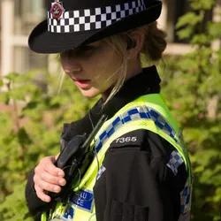 a policing student stood in uniform talking into a radio