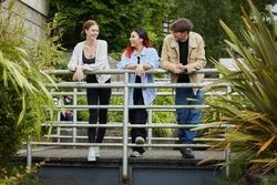 Three students laugh together while stood on a small bridge over a pond at Treforest campus