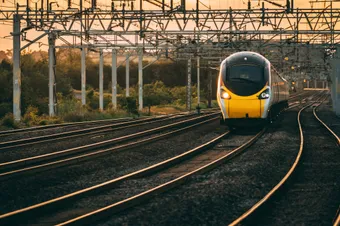 A train travelling along train tracks with the sun setting in the background.