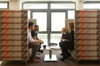 Four people having a business conversation in a meeting booth