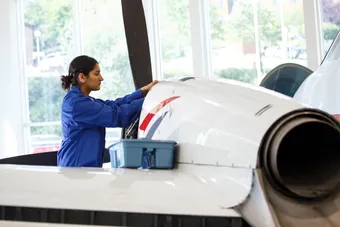 Female student examining an aircraft propeller.
