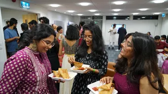 Three female students dressed in traditional indian dress eating street foot
