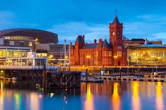 Cardiff Bay at dusk, the Pierhead building and the Senedd can be seen over the water.
