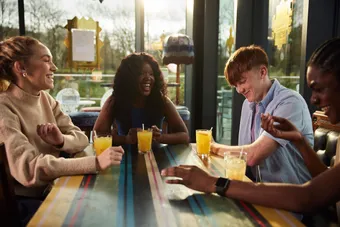 A group of students happily chatting over a drink in sunny window of a restaurant in Pontypridd.