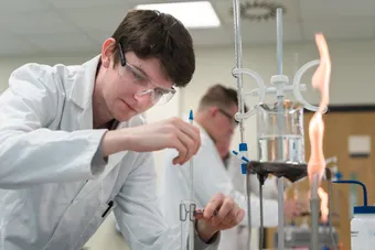 male student using equipment in chemistry lab