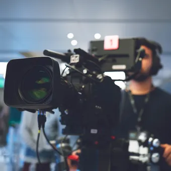 Student wearing headphones operating a film camera