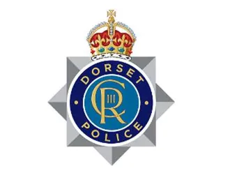 The Dorset Police logo - a silver police star badge style crest with the logo of King Charles third in the middle with the words 