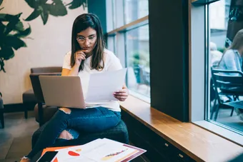 A student reading of her application form with a laptop resting on her knee