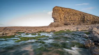 Nash Point, south Wales, with a stream of water running beneath the cliff face