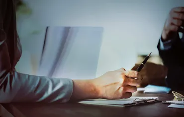 person sitting at a desk with pen in hand