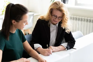 A business woman signing a document at a table