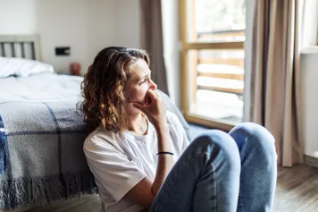 Young adult woman sitting at home alone looking worried