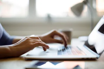 Hands of an unrecognisable person typing on a laptop