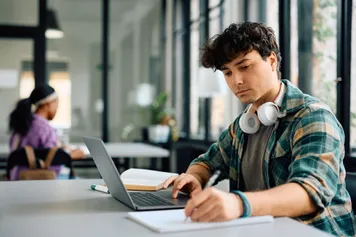 person sitting at a desk writing in a notebook