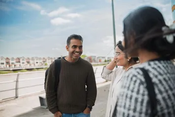 Students talking outside Newport campus with views of the river in the background.