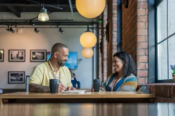 A man and a woman having a conversation over coffee at Ty Crawshay's cafe