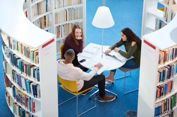 Three students sat in Newport campus library studying together