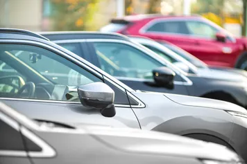A side view of a various cars parked in a line in a carpark