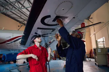 Two students working together to examine an aircraft wing.