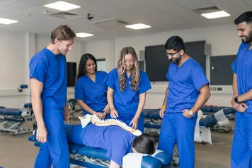 Students surrounding a Chiropractic table.