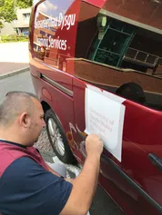 print and design staff member applying a display graphic of the USW logo to a van