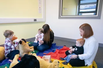 Two students play with toddlers with toys as part of their research in the USW Observation Suite at Glyntaff Campus