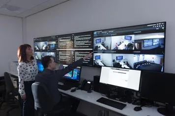 Two policing lecturers observing the screens in the hydra simulation centre on glyntaff campus
