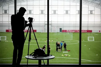 Shot of photographer looking down at students during a practical session on the pitch