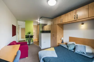 A studio room in pontypridd with a double bed, armchair and breakfast bar.