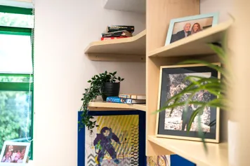 close up of a shelf in a student halls bedroom containing photographs of family, artwork and plants