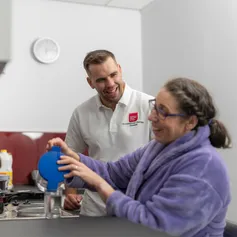 Occupational Therapy student smiling whilst patient pours water in to a glass