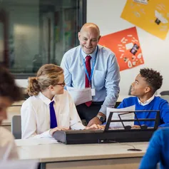 A teacher engaging with two children in a classroom