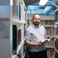 Student holding book in library