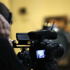 A close up of a large TV camera filming inside a yellow room