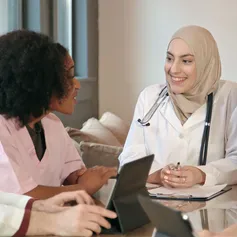 A doctor and nurse smiling and chatting during a meeting