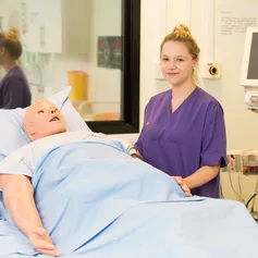 Nursing student stood next to a patient simulator in the clinical simulation centre