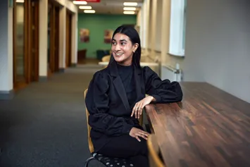 Student Sumaya Khan sits at a table and smiles at the postgraduate centre in Treforest