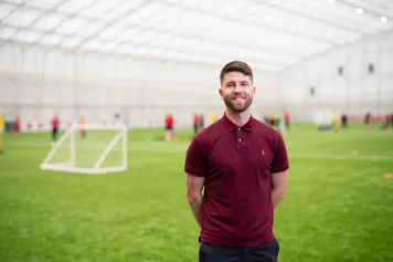 PhD Student Lee Baldock standing on football pitch