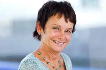 A professional photograph of Dr Bev John smiling at the camera.
