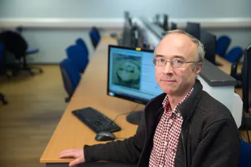 Professor Douglas Tudhope smiling at the camera in one of the University computer labs.