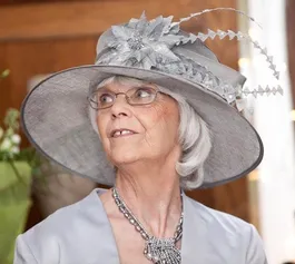 Violet Burns dressed in a formal hat and dress smiling