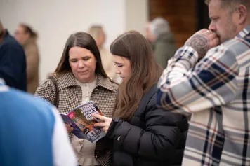 Open day visitors looking through an event leaflet.