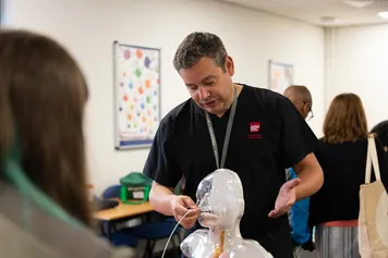 A lecturer is demonstrating nursing equipment at an Open Day.