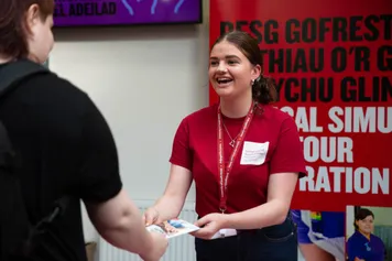 A student ambassador handing out leaflets at the open day registration desk.