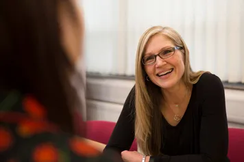 A member of staff is smiling and chatting with an open evening visitor.
