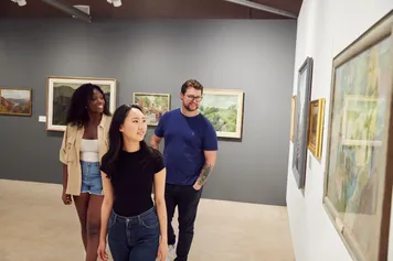 A group of happy students looking at paintings at a gallery in Newport.