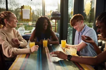 A group of students happily chatting over a drink in sunny window of a restaurant in Pontypridd.