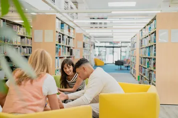 Students sat together in Glyntaff library, studying and socialising.